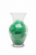 Clear glass vase filled with green decorative gem stones on white background